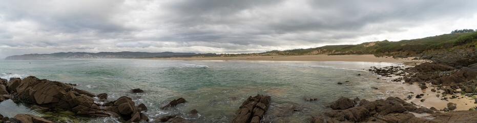 beautiful beach in Spain with sand and rocky pools under an expressive sky