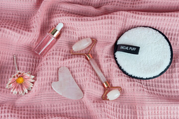 Jade face roller and Gua sha stone for facial massage. Home skin care anti-aging tools, face serum bottle, massage roller. Natural organic essential oil, skincare beauty product. Flat lay, top view.