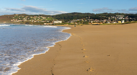 footprints in the sand on a beautiful beach and woman walking in the distance