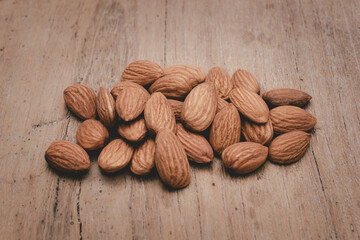 Almonds are placed on the wooden floor at the center of the image, copy space.