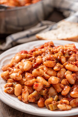 White beans with spicy tomato sauce in a white ceramic plate close-up. Greek style food, Mediterranean cuisine. Tasty vegetarian food with white beans.
