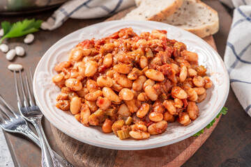 White beans with spicy tomato sauce in a white ceramic plate close-up. Greek style food, Mediterranean cuisine. Tasty vegetarian food with white beans.
