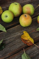 Green apples and autumn leaves on the table