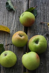 Green apples and autumn leaves on the table