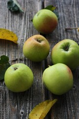 Naklejka na ściany i meble Green apples and autumn leaves on the table
