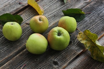 Green apples and autumn leaves on the table