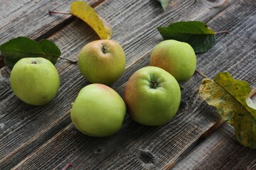 Green apples and autumn leaves on the table