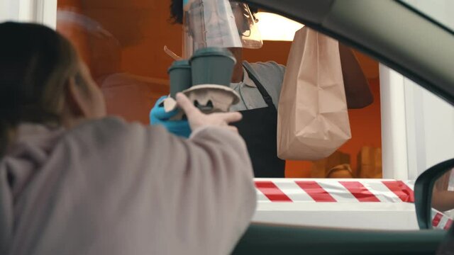 Woman driver taking coffee and meal at drive thru during coronavirus outbreak