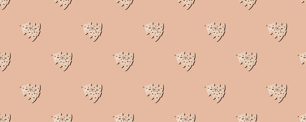 New Year's composition. Trendy Christmas pattern from wooden Christmas trees with a hard shadow on a sand-colored background. Flat lay, top view. Creative minimal christmas art.