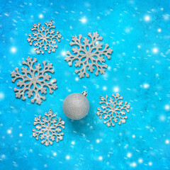 Fototapeta na wymiar Silvery snowflakes and Christmas ball on a turquoise grunge background. Christmas decorations on a blue rustic background. Top view.