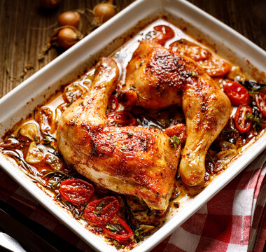 Roasted Chicken Leg Quarters  With Herbs And Spices Served In A Baking Dish Close Up View