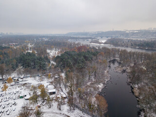 Aerial drone view. Snow-covered trees in the park. A thin layer of the first snow on earth.