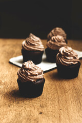Chocolate muffins with cream on a wooden background. Homemade muffins. Sweet