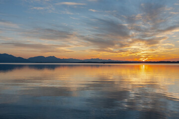 Naklejka premium Sonnenuntergang am Chiemsee mit Wolken , Spieglung und Bergen