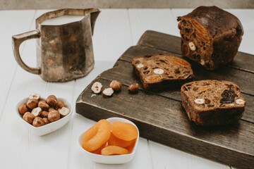 a mug of milk and bread with dried fruit on a light background 