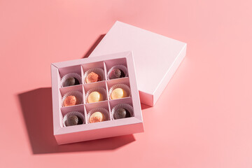 Chocolate candies in a festive box on a pink background. Holiday concept