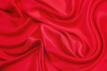 Fototapeta na wymiar Shining red silk atlas satin fabric with folds, fabric waves. Red pink fabric background. Close up