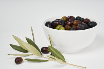 Olive branches and freshly picked green and black olives photographed on a white background.