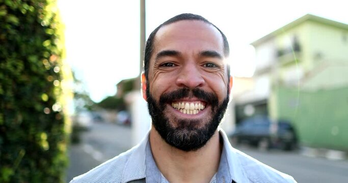 Casual Happy hispanic man in 40s smiling at camera outside in urban street