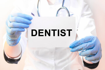 The doctor's blue - gloved hands show the word DENTIST - . a gloved hand on a white background. Medical concept. the medicine