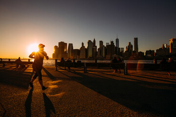 Silhouette of jogger young fit woman running at sunset at sunset on the Hudson River boardwalk in New York City