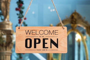 Welcome Open sign wood board hanging with the glass door front of cafe