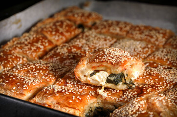 Burekas. Puff pastry pies with spinach with spinach, salted cheese, and sesame
