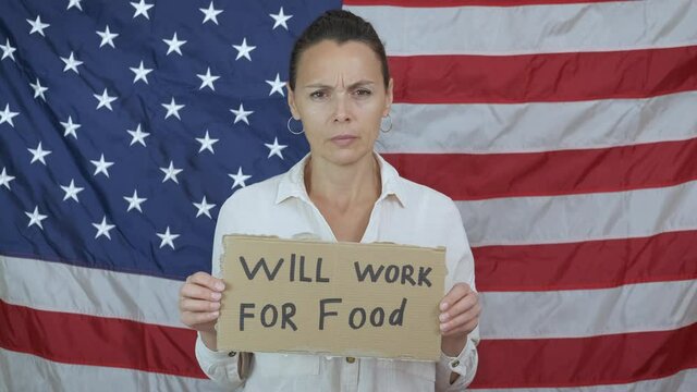 Hungry woman look for job. A workless sad woman looking for a job anf food with a cardboard on the background of American flag.