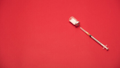 syringe with vaccine bottle, red background