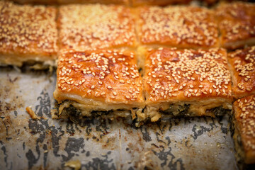Obraz premium Burekas. Puff pastry pies with spinach with spinach, salted cheese, and sesame