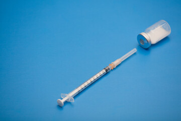 syringe with vaccine bottle, blue background