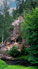 Sandstone Caves in Ligatne, Latvia. View to Cave Rock Lustuzis (Lustūzis) on the Bank of Ligatne River. Caves With Old Wooden Doors.