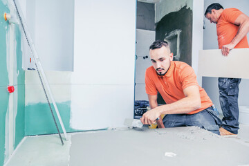 
Fliesenleger installiert großformatige Fliesen an der Wand. Haus Renovierung