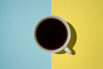 Creative concept top view a cup of coffee on light blue and yellow background
