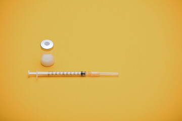 syringe with vaccine bottle, yellow background