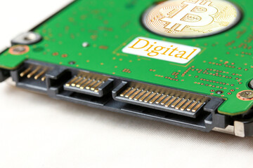 The harddisk is placed on a white background and there is a blurred and defocused overlay of the golden Bitcoin coin.