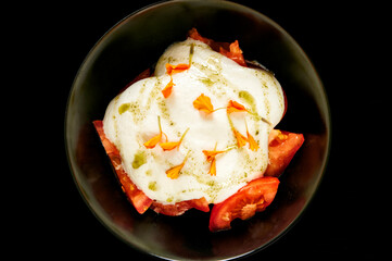 Tomato salad with cheese in dark Bowl