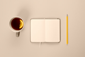 Tea cup and fancy notebook with empty or blank page on desk from above. Mock up toned in trendy 2021 color.