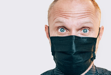 Portrait of surprised man in black facial mask during a COVID-19 world pandemic looking at camera. Self-protection and stop virus spreading measures concept image