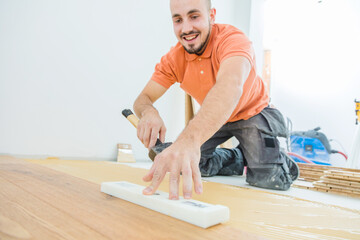 A Male Worker install wood floor on a house