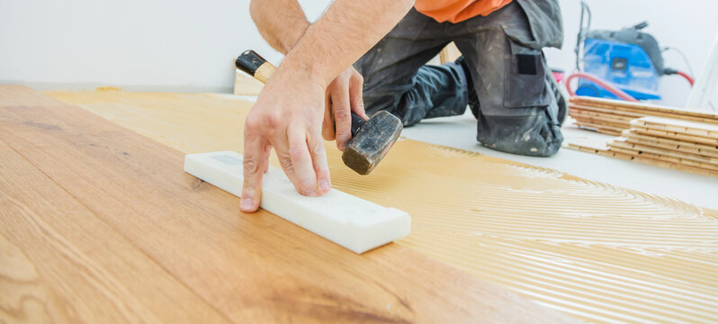 A Male Worker install wood floor on a house
