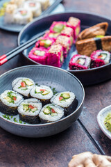 Delicious rolls, sushi and maki on a dark wooden Board with chopsticks. On black rustic background