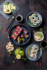 Delicious rolls, sushi and maki on a dark wooden Board with chopsticks. On black rustic background