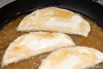 Three very appetizing pasties are fried in hot oil.