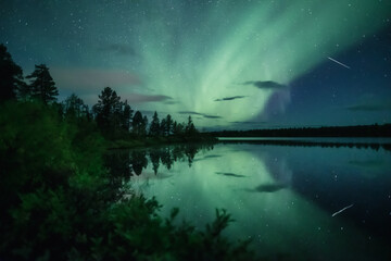 Shooting star and auroras reflecting from a still lake