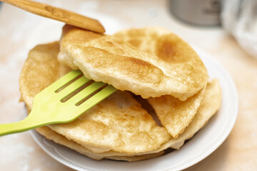 The girl carefully lays down the finished cheburek on a plate to other ready-made chebureks.