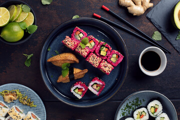 Delicious rolls, sushi and maki on a dark wooden Board with chopsticks. On black rustic background