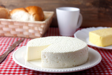 fresh white brazilian minas cheese isolated over wooden board on breakfast table. front view