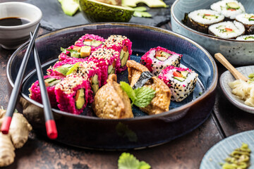 Delicious rolls, sushi and maki on a dark wooden Board with chopsticks. On black rustic background
