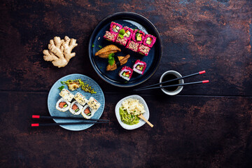 Delicious rolls, sushi and maki on a dark wooden Board with chopsticks. On black rustic background